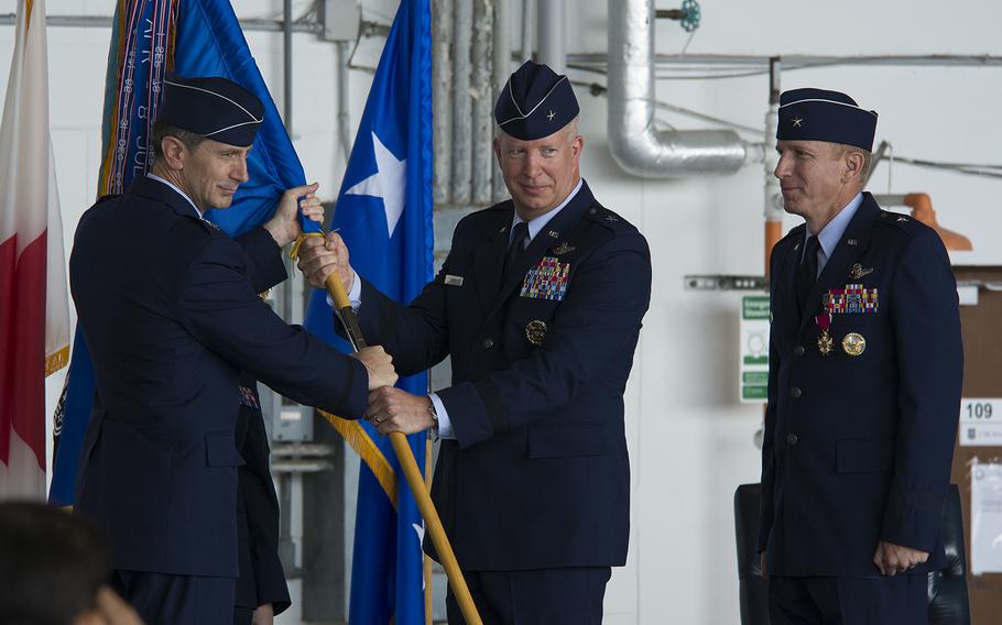 Lt. Gen. Kevin Schneider of U.S. Forces Japan, left, hands the colors to Brig. Gen. Joel Carey, who took command of the 18th Wing from Brig. Gen. Case Cunningham, right, at Kadena Air Base, Okinawa, Monday, July 8, 2019.