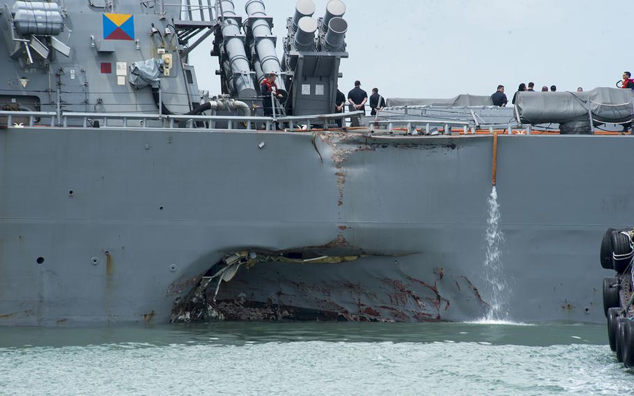 Damage to the portside is visible as the guided-missile destroyer USS John S. McCain steers toward Changi Naval Base, Singapore, following a collision with a merchant vessel east of the Straits of Malacca and Singapore, Aug. 21, 2017.