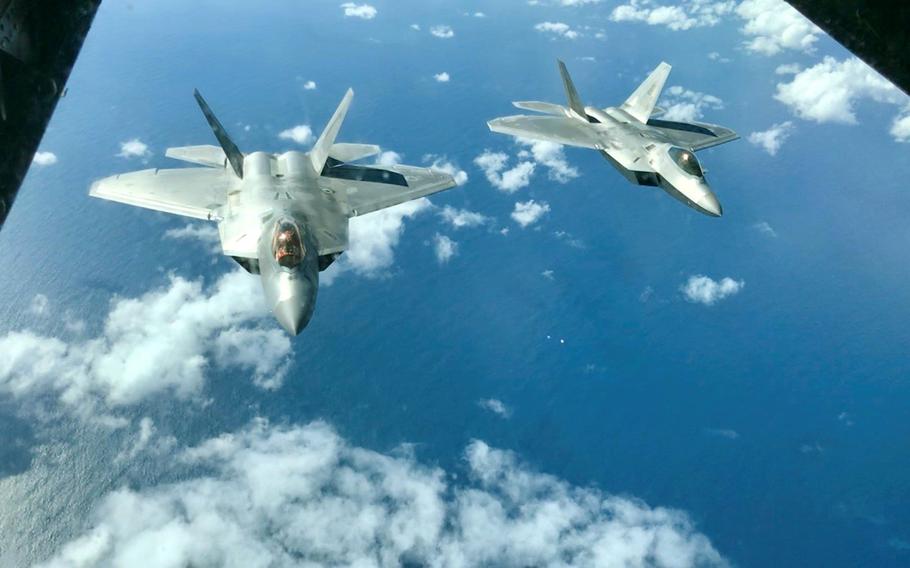 A pair of F-22 Raptors fly behind a KC-10 Extender above the Coral Sea during Talisman Sabre drills in Australia, Friday, July 19, 2019.