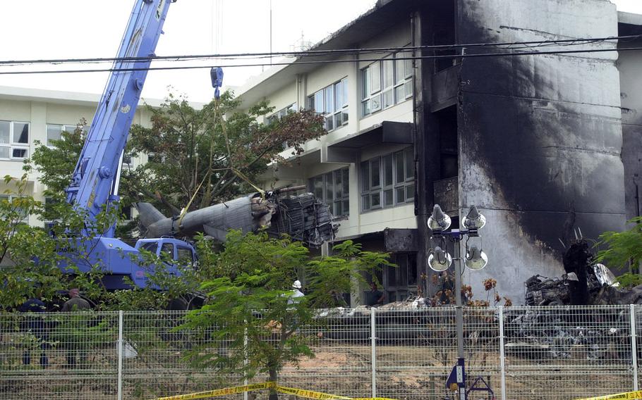 Pieces of a CH-53D Sea Stallion are removed from a crash site at Okinawa International University on Aug. 16, 2004.