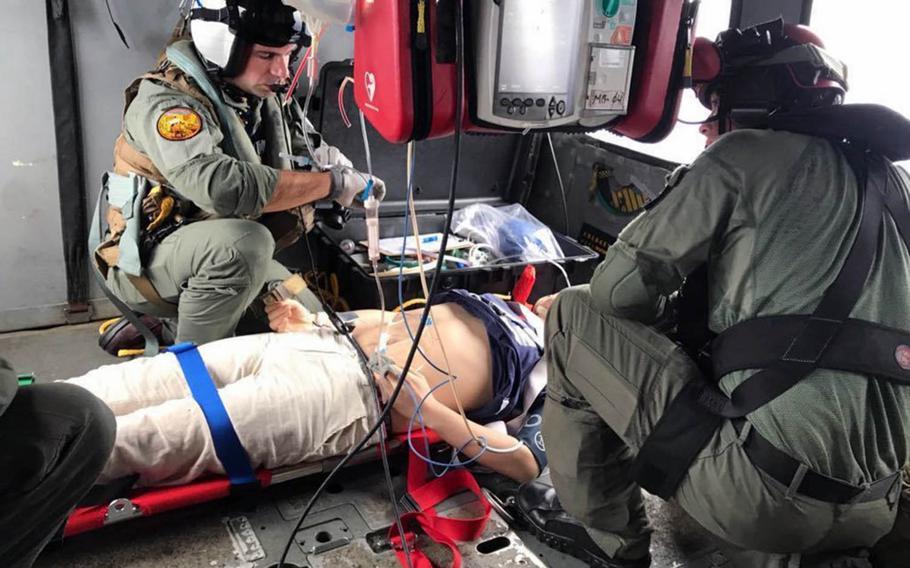 Lt. Erik Kumetz and Petty Officer 2nd Class Kyle Bowen of Helicopter Sea Combat Squadron 25, Guam, provide medical care to a Chinese mariner on Tuesday, Aug. 6, 2019.