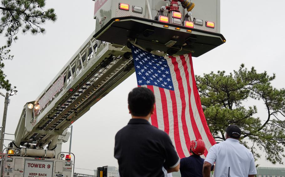 Firefighters prepare to hoist an American flag during the ninth annual 9/11 Memorial Ruck March at Camp Humphreys, South Korea, Wednesday, Sept. 11, 2019.