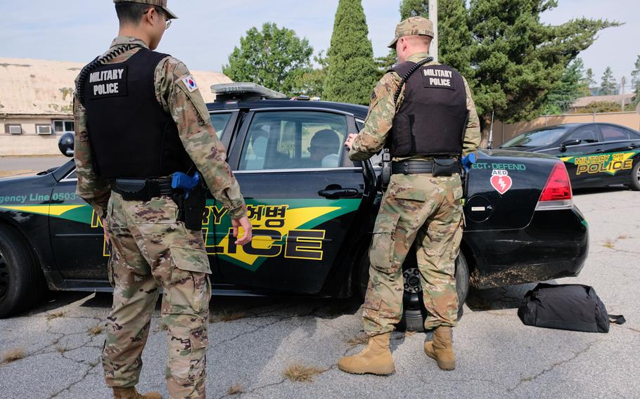 Soldiers from the 142nd Military Police Company place a servicemember role-playing a suspect into a cruiser during a training exercise at Yongsan Garrison, South Korea, on Thursday, Sept. 26, 2019.