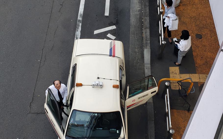 A taxi driver returns to his vehicle outside Fussa Station, near Yokota Air Base, Japan, Tuesday, Oct. 1, 2019.