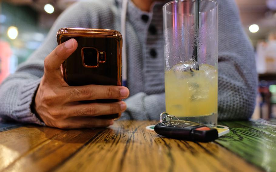 A bar customer uses his phone after consuming an alcoholic beverage near Osan Air Base, South Korea, Sunday, Oct. 6, 2019.