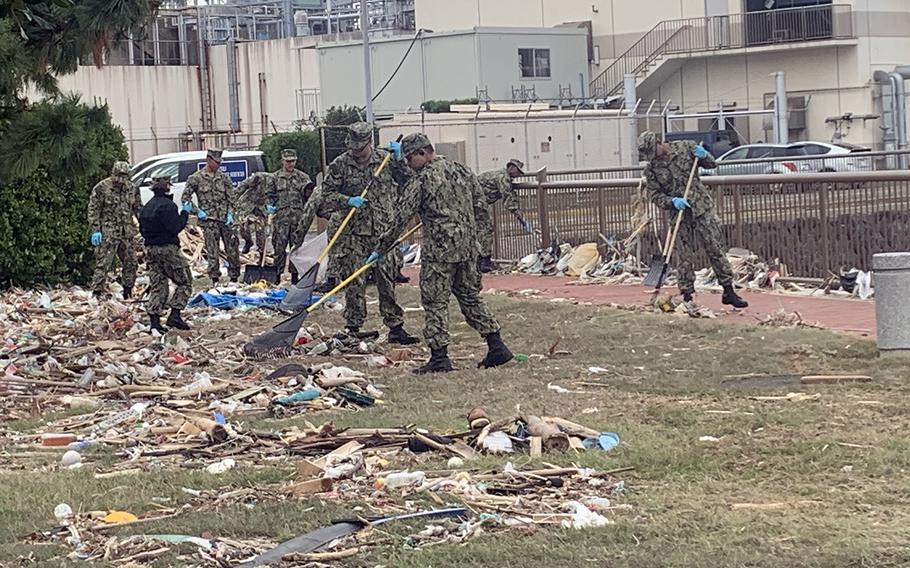 Sailors rake debris at Yokosuka Naval Base, Japan, Tuesday, Oct. 15, 2019, days after deadly Typhoon Hagibis ripped through the area.