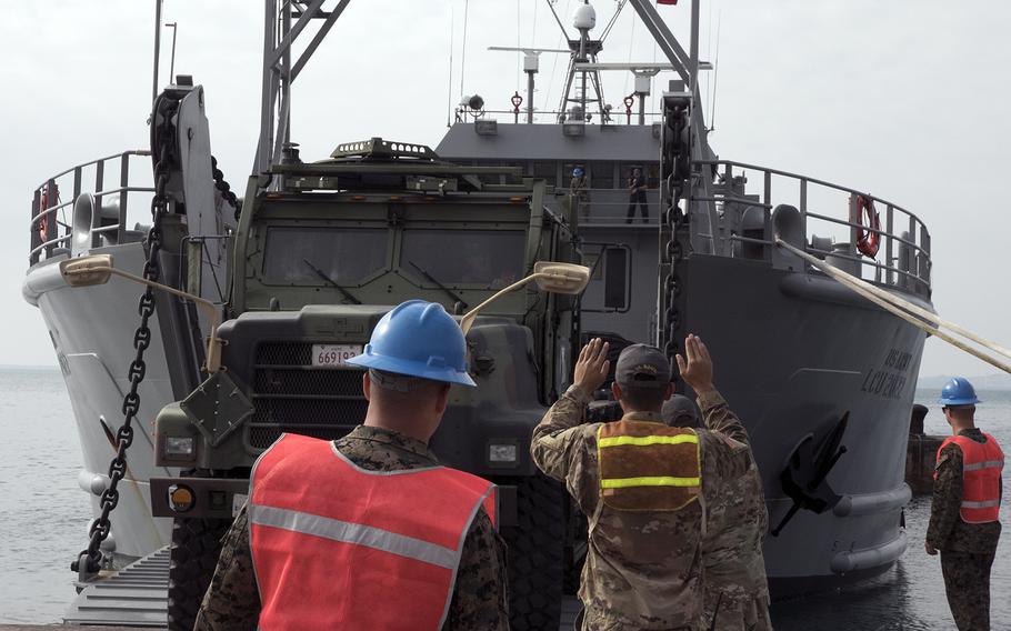 Soldiers with the Army's 10th Support Group back a Marine Corps vehicle onto the USAV Harpers Ferry during a joint training drill at Kin, Okinawa, Thursday, Oct. 31, 2019.