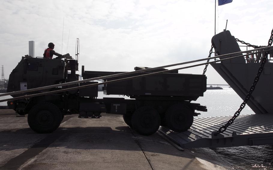 A member of the 12th Marine Regiment HIMARS platoon backs a launcher onto an Army vessel at Kin, Okinawa, Thursday, Oct. 31, 2019.