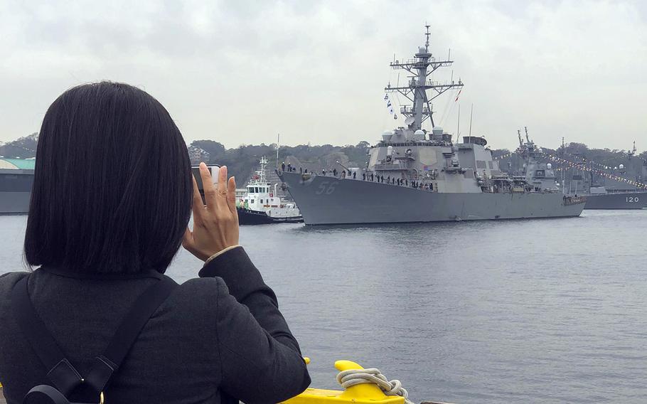 A woman takes a photo of the USS John S. McCain as the guided-missile destroyer arrives back at Yokosuka Naval Base, Japan, Sunday, Nov. 3, 2019, after a week of sea trials.