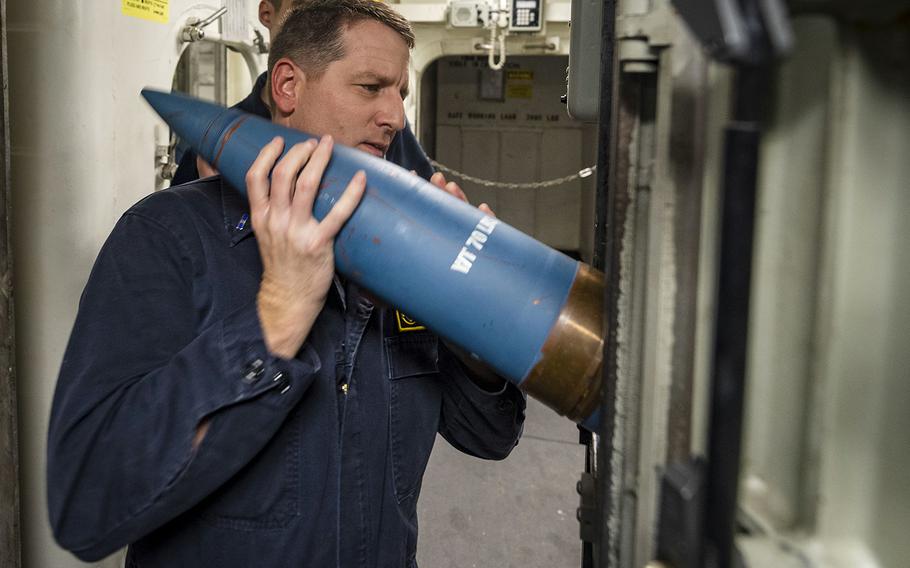 Chief Warrant Officer 3 Joshua Patat loads ammunition into an ammo hoist for a live-fire drill aboard the guided-missile destroyer USS John S. McCain in the Philippine Sea, Wednesday, Oct. 30, 2019.