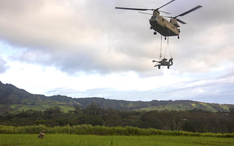 A CH-47 Chinook helicopter transports a howitzer over a range at Schofield Barracks, Hawaii, Oct. 10, 2019.