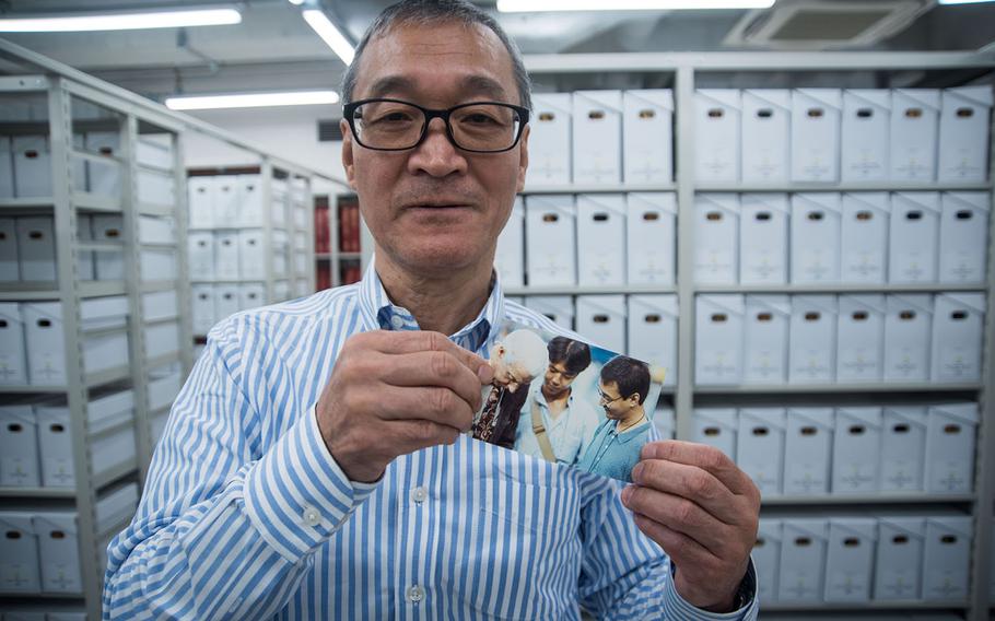 Stars and Stripes librarian Norio Muroi holds a photo of himself, far right, meeting Yankees legend Joe DiMaggio during a reporting assignment in Tokyo in the early 1990s.