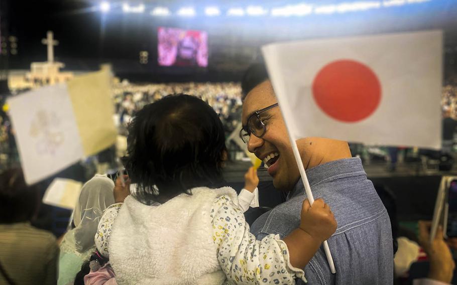 Lt. Cmdr. Ryan de Vera, a public affairs officer at Yokosuka Naval Base, Japan, holds his 1-year-old daughter, Avery, as they wait to see Pope Francis at the Tokyo Dome on Monday, Nov. 25, 2019.