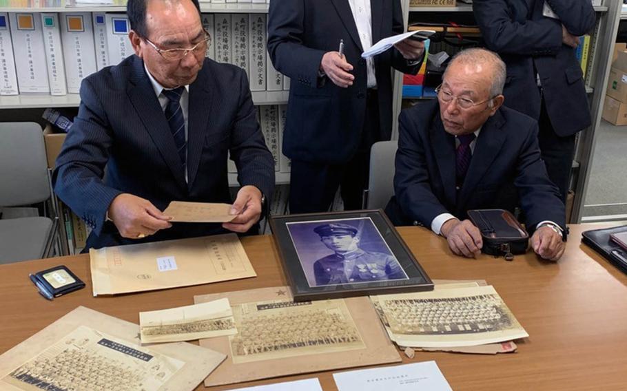 Akitaka Nagasawa, left, shows photographs of his uncle Yoshio Nagasawa, whose portrait in uniform is at center. Yoshio Nagasawa's World War II-era flag was returned to his family in Japan on Monday, Nov. 25, 2019.