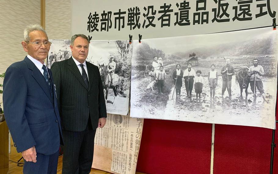 Tamotsu Shikata, left, and Jarat Chopra stand before a photograph of Shikata and his family carried by his brother Hideo Shikata during World War II. Chopra returned an album of his brother's photographs to Shikata in Ayabe, Japan, on Sunday, Nov. 24, 2019.
