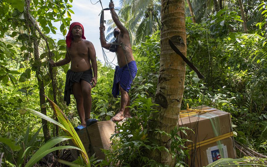 Villagers stand atop humanitarian aid bundles airdropped to the island of Woleai, Micronesia, during Operation Christmas Drop, Tuesday, Dec. 10, 2019.