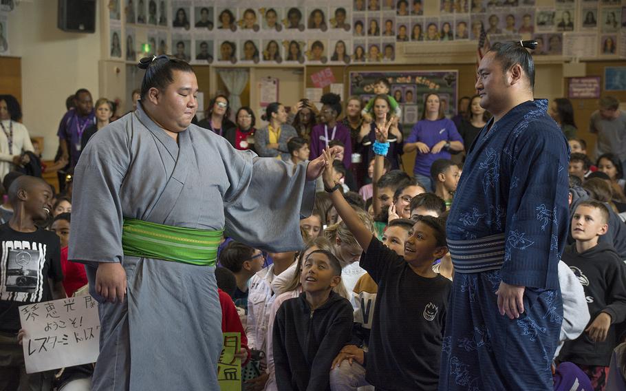 Sumo wrestler Kotoeko, right, watches as Kotooodutsu high-fives a Lester Middle School student at Camp Lester, Okinawa, Friday, Dec. 13, 2019.