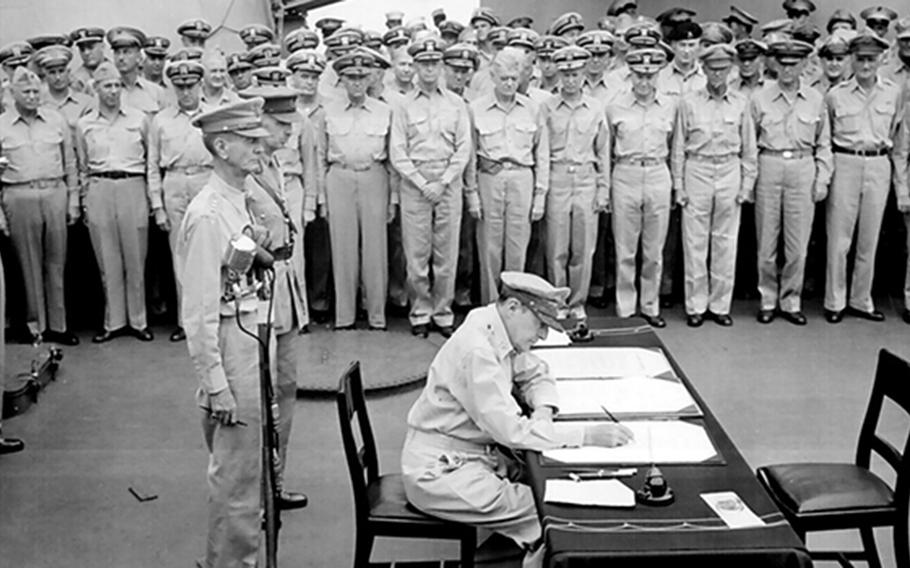 Allied sailors and officers watch Gen. Douglas MacArthur sign documents during the surrender ceremony aboard USS Missouri that ended World War II on Sept. 2, 1945.