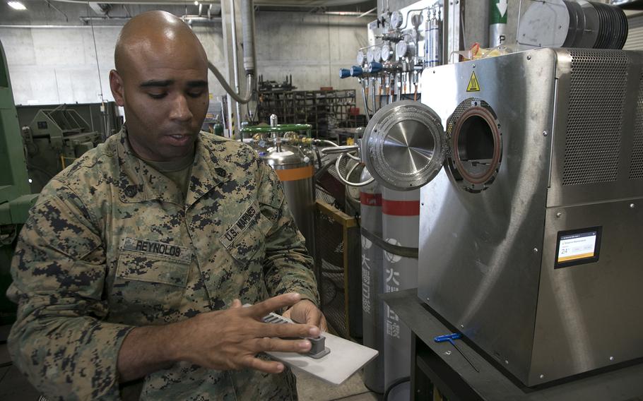 Marine Staff Sgt. Quincy Reynolds of the III Marine Expeditionary Force's 3rd Maintenance Battalion shows off the furnace for the unit's new Markforged Metal X 3D printer at Camp Kinser, Okinawa, Jan. 16, 2020.
