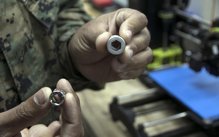 Marine Staff Sgt. Quincy Reynolds of the III Marine Expeditionary Force's 3rd Maintenance Battalion holds two sockets inside his shop at Camp Kinser, Okinawa, Jan. 16, 2020. The one on the right was made with the unit's new Markforged Metal X 3D printer.