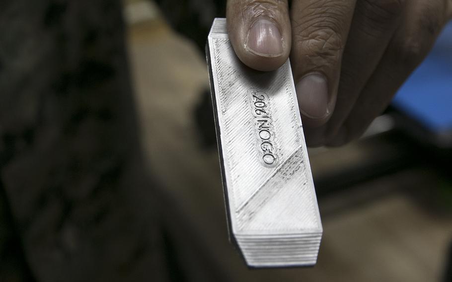 Marine Staff Sgt. Quincy Reynolds of the III Marine Expeditionary Force's 3rd Maintenance Battalion holds a .50 caliber machine gun gauge made by their new metal 3D printer at Camp Kinser, Okinawa, Jan. 16, 2020.