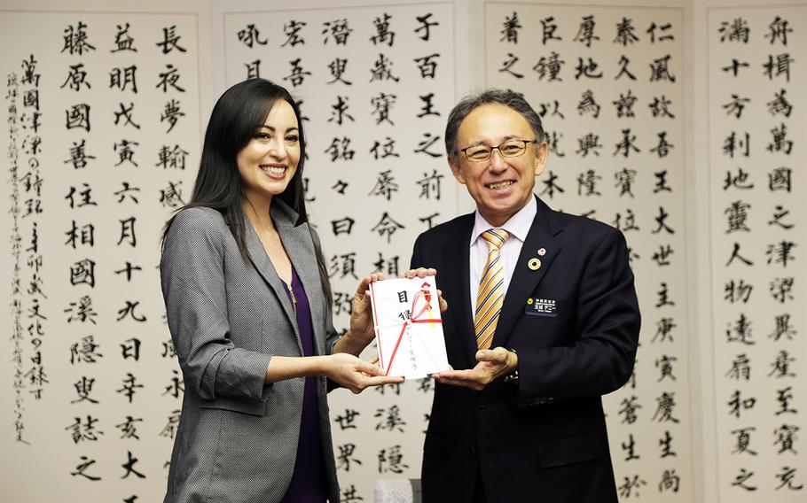 Marine Corps spouse Mari Gregory presents Okinawa Gov. Denny Tamaki with more than $11,000 in donations for the restoration of Shuri Castle, Thursday, Feb. 6, 2020. The popular cultural landmark was devastated by fire in October.