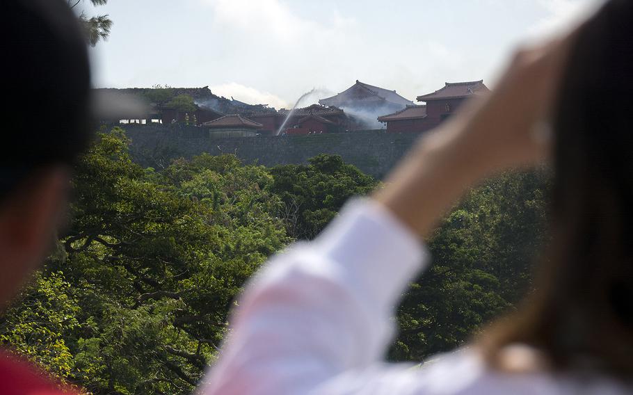 People watch as firefighters work a blaze at Shuri Castle in Naha, Okinawa, Oct. 31, 2019.