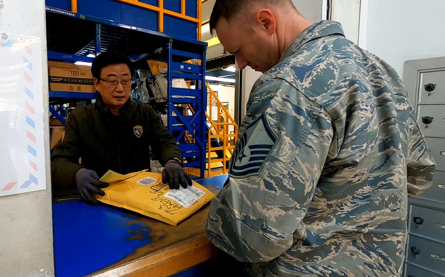 A South Korean man working for U.S. Forces Korea assists a service member at the post office on Osan Air Base, South Korea, Thursday, Feb. 6, 2020.