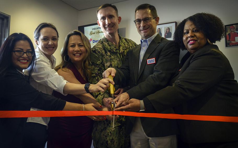 The USO Yokosuka team helps base commander Capt. Richard Jarrett and USO Pacific Region Vice President Charles Hyde cut the ribbon to reopen the renovated facility at Yokosuka Naval Base, Japan, Friday, Feb. 7, 2020.