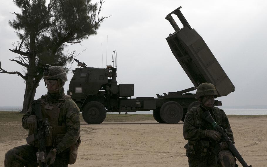 A U.S. Marine, left, and a Japan Ground Self-Defense Force soldier guard an M142 High Mobility Artillery Rocket System during an exercise in Kin, Okinawa, Sunday, Feb. 9, 2020.
