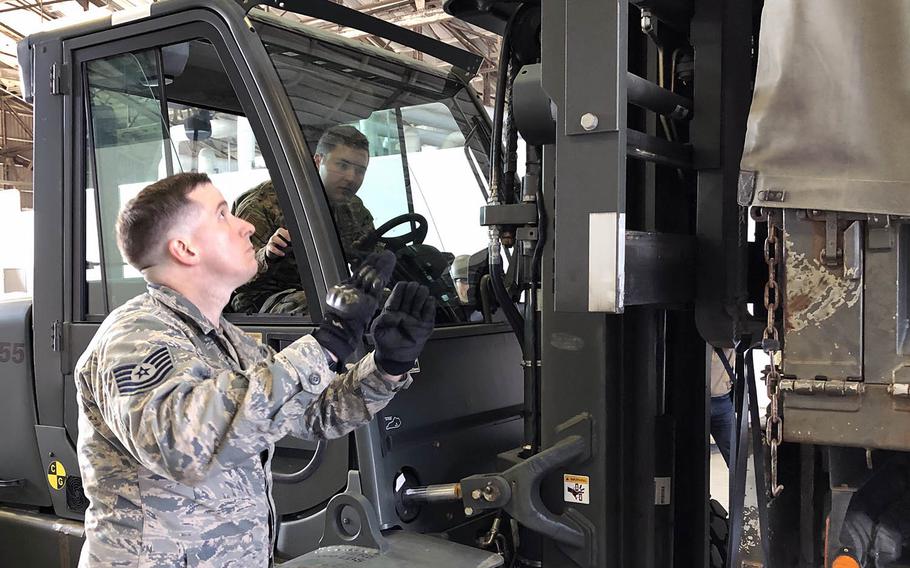 Air Force Tech. Sgt. Daniel Blair guides Staff Sgt. William McAtee as he unloads Meals, Ready to Eat from a Japan Ground Self-Defense Force truck at Yokota Air Base, Japan, Friday, Feb. 21, 2020.