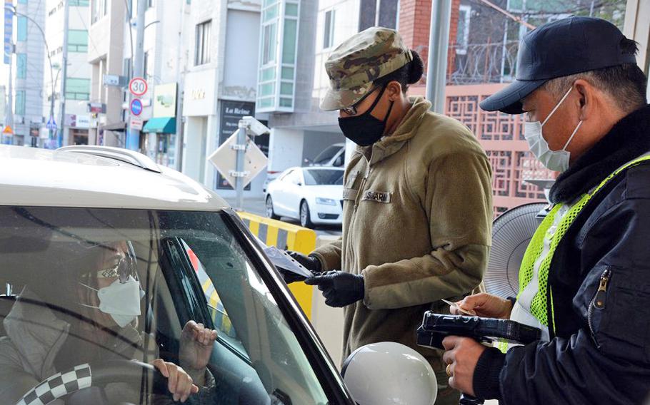 Pvt. Daija Gillam, 22, of the 25th Transportation Battalion, screens drivers before allowing them to enter Camp Walker in the coronavirus-hit city of Daegu, South Korea, Saturday, Feb. 22, 2020.
