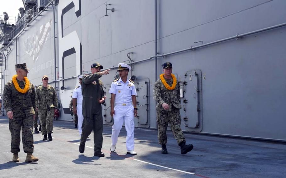 U.S. Navy Cmdr. Stephen Audelo, pointing, guides Royal Thai Navy Capt. Arpa Chapanon during a tour of the amphibious assault ship USS America in Laem Chabang, Thailand, Feb. 22, 2020.