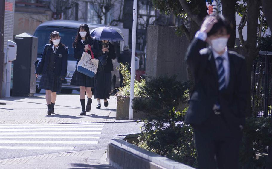 Students in central Tokyo wear face masks to guard against the coronavirus, Thursday, March 12, 2020. 