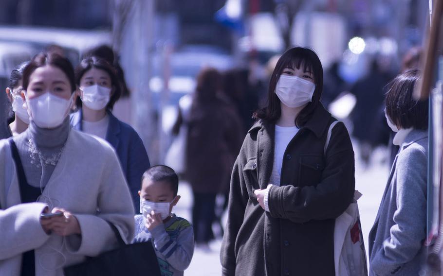 People wear face masks in the Omotesando area of central Tokyo, Monday, March 16, 2020.