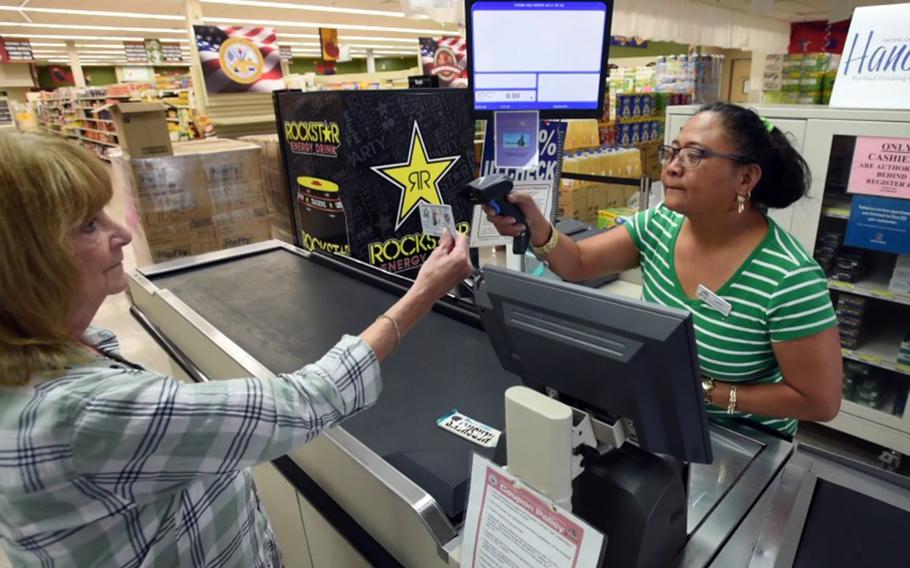 Leslie Carroll, left, director of the Orote Commissary at Naval Base Guam, demonstrates new touchless ID procedures in this screenshot from a video posted by the installation Tuesday, March 17, 2020.