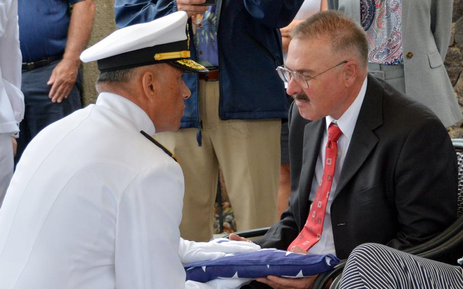 Rear Adm. Darius Banaji, deputy director of the Defense POW/MIA Accounting Agency, gives the interment flag to William Hall, nephew of Seaman 2nd Class Hubert P. Hall, who was killed aboard the USS Oklahoma in 1941 and buried March 17, 2020, at the National Memorial Cemetery of the Pacific, Hawaii.