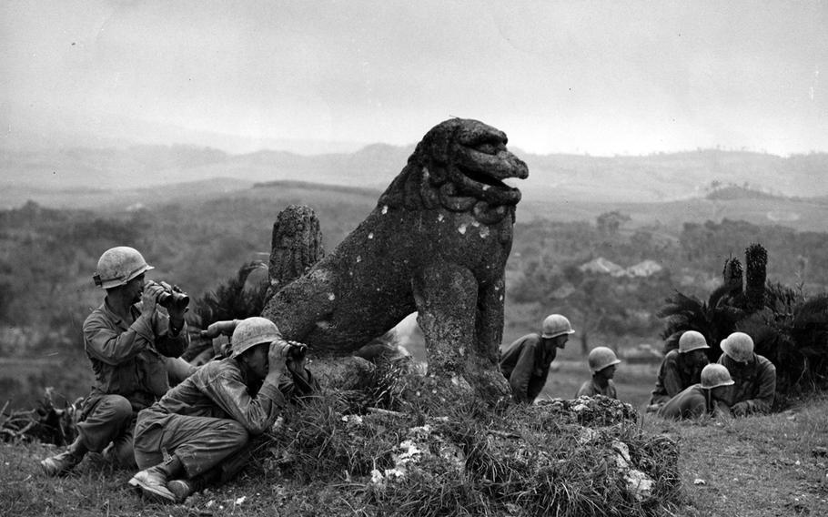 American troops take cover behind a bullet-pocked statue during the Battle of Okinawa. The ferocious 82-day battle lasted from April 1 until June 22, 1945.