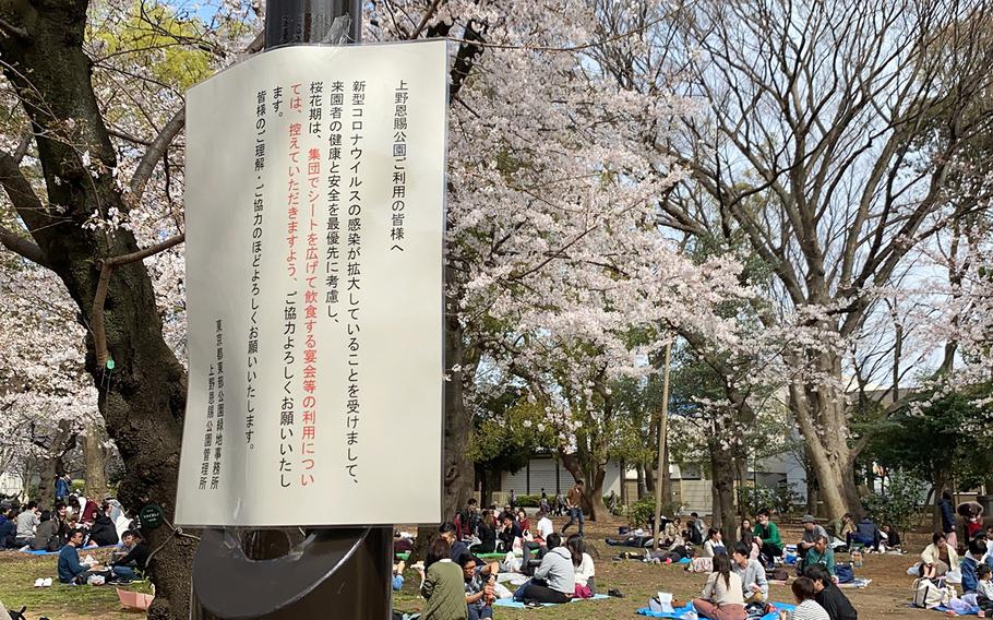 A sign asks visitors to Ueno Park in Tokyo to "refrain from putting out picnic sheets and having parties where you eat and drink in groups during the cherry blossom season," Sunday, March 22, 2020.