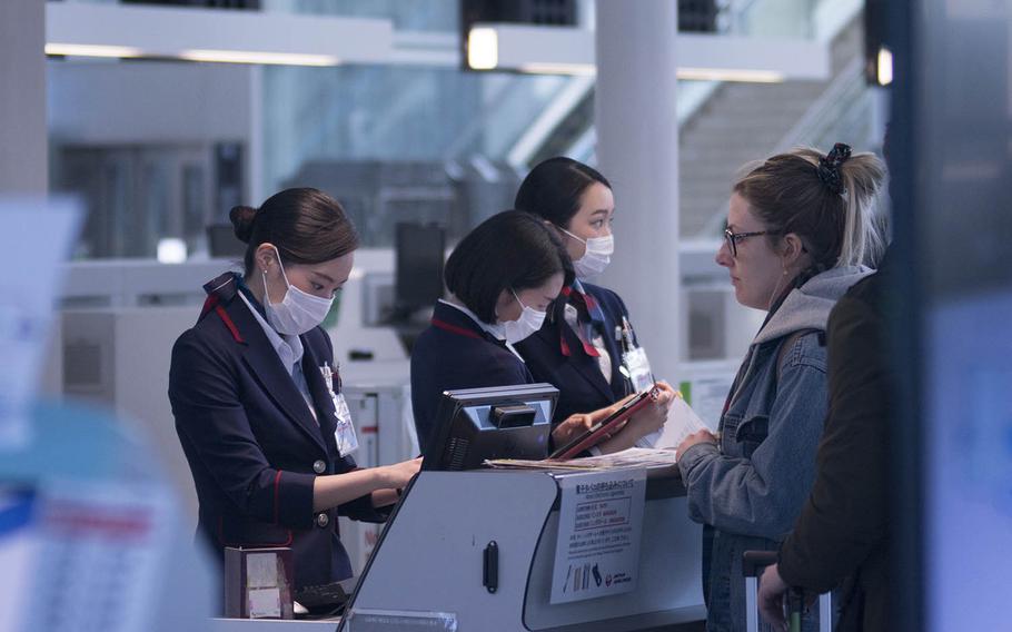 An airline employee helps a customer check in for a flight out of Haneda International Airport in Tokyo, March 18, 2020.