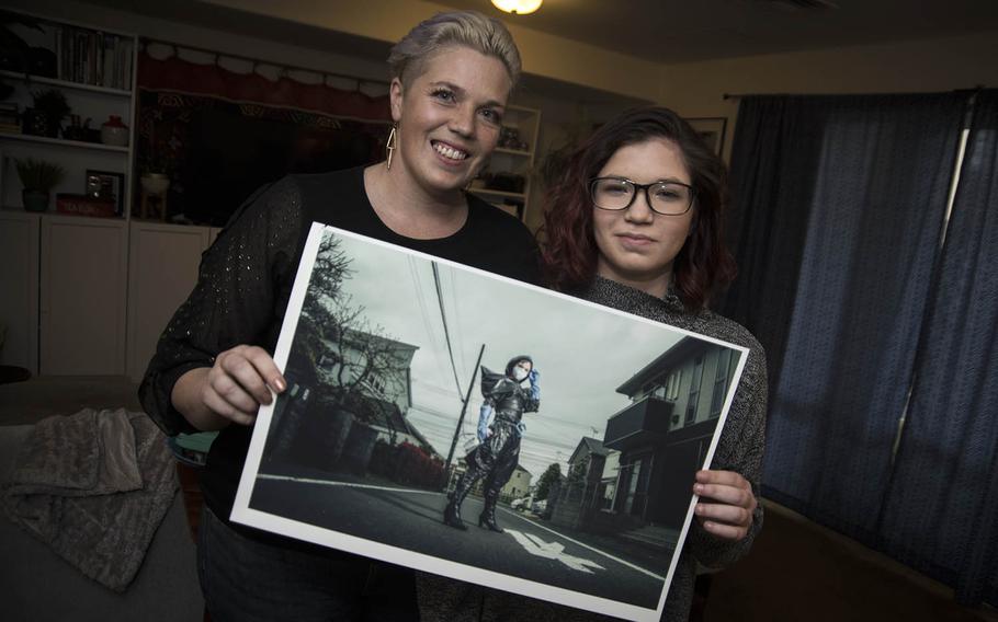 Cari Payer and her daughter, Sage, pose with an image from their coronavirus photo project inside their home at Yokota Air Base, Japan, Wednesday, April 1, 2020.