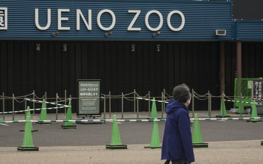 A woman walks in front of Ueno Zoo, which has been closed because of the coronavirus pandemic, in central Tokyo, Monday, March 30, 2020.