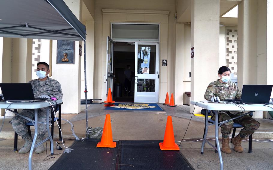 A pair of pharmacy technicians with the 15th Wing practice social distancing as they check in pharmacy patients at Joint Base Pearl Harbor-Hickam, Hawaii, March 26, 2020.