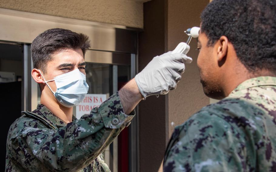 A hospital corpsman checks the temperature of a sailor visiting a health clinic at Naval Air Facility Atsugi, March 26, 2020.