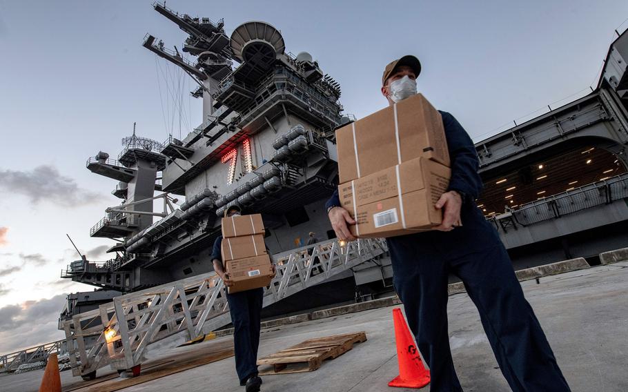 Sailors assigned to the aircraft carrier USS Theodore Roosevelt move meals, ready to eat for shipmates who have tested negative for the coronavirus at Naval Base, Guam, April 7, 2020.