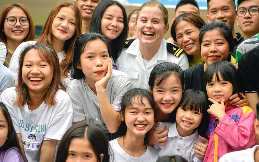 A Navy public affairs officer poses for a photo with children at the Dorothea's Project Legacies Charity Center, Danang, Vietnam, during the USS Theodore Roosevelt's port call March 6, 2020.