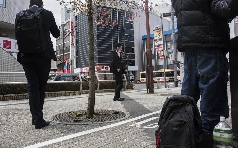 Smokers practice social distancing at a smoking area outside the main train station in Fussa, Japan, Friday, April 17, 2020.