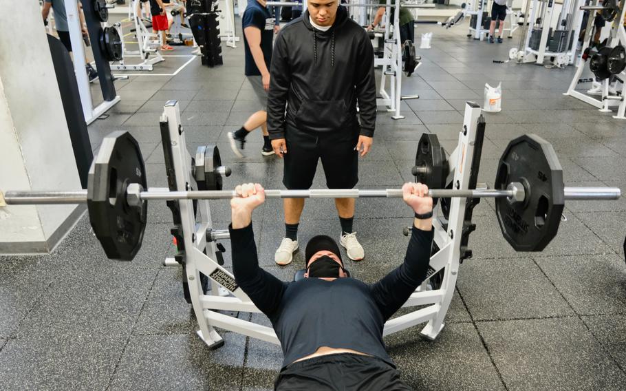 Staff Sgt. Elvis York lifts weights wearing a mask while his spotter maintains proper social distance inside Collier Community Fitness Center at Camp Humphreys, South Korea, Saturday, April 18, 2020.