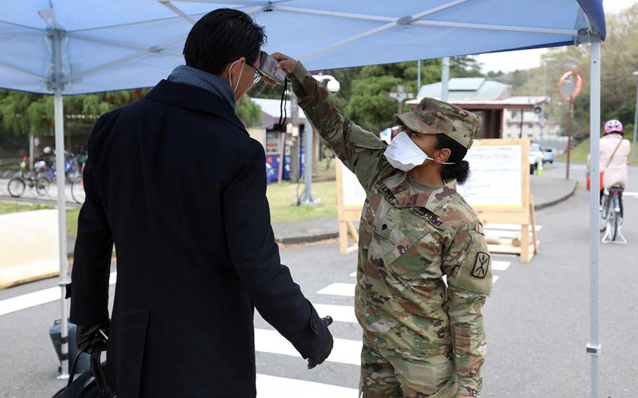 Spc. Brittany Farley takes the temperature of a man entering Camp Zama, Japan, March 31, 2020.