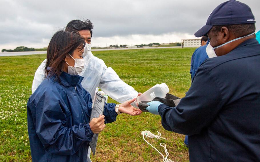 Marine Corps environmental specialists give water samples to officials from the Okinawa Defense Bureau at Marine Corps Air Station Futenma, Okinawa, Tuesday, April 21, 2020.